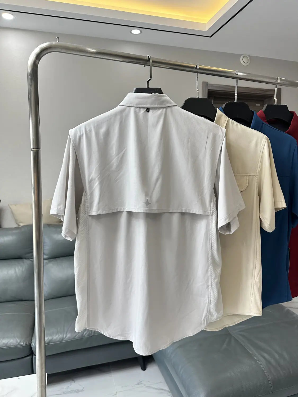 Weißes Herren-Stretch-Outdoorhemd mit kurzen Ärmeln, Kragen und zweilagigem Design aus schnelltrocknendem Material, präsentiert auf einem Bügel