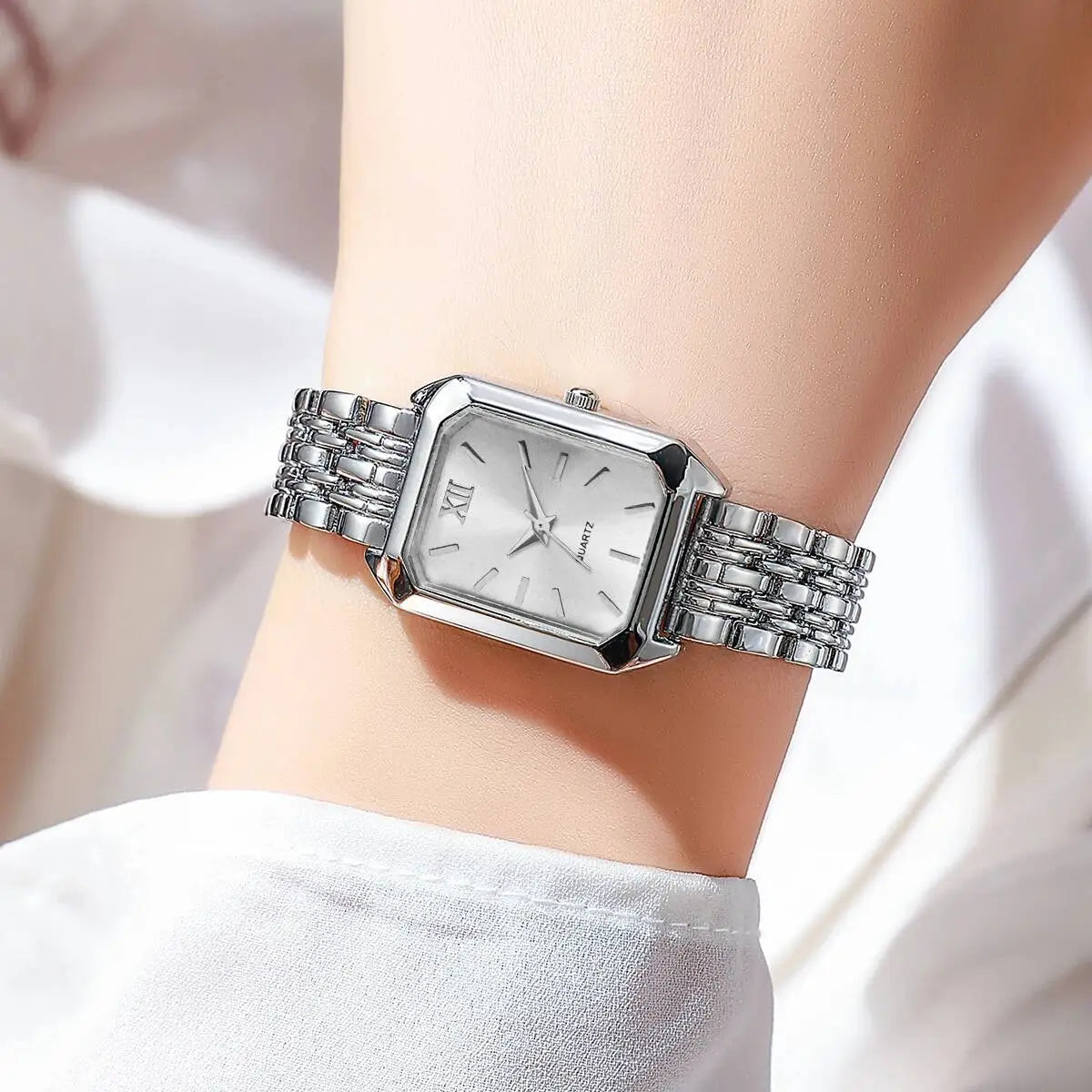Women gold rectangle quartz watch with a silver rectangular quartz face featuring a sleek metallic bracelet and minimalist dial with roman numerals.