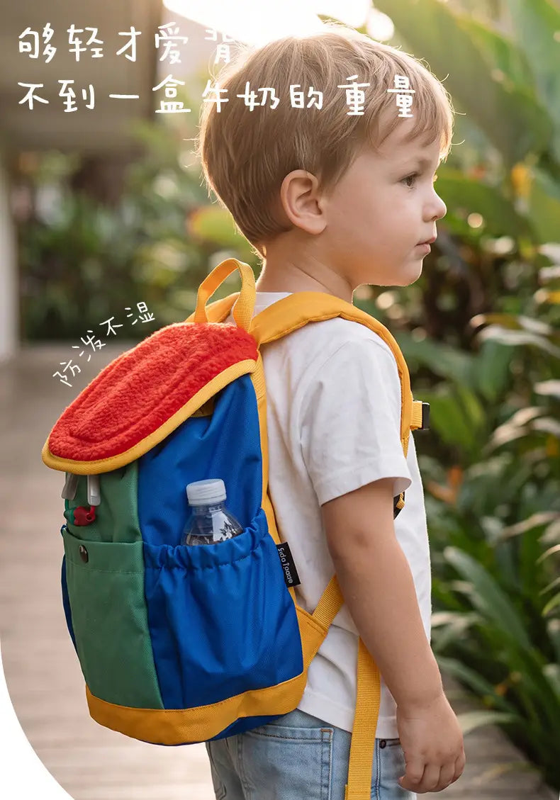 Leichter Fuzzy-Rucksack für Kinder mit einem farbenfrohen Design: Plüschroter und gelber Oberteil, blauer Hauptkörper, grüne Seiten-Tasche und leuchtend gelbe Träger für die tägliche Verwendung im Kindergarten.