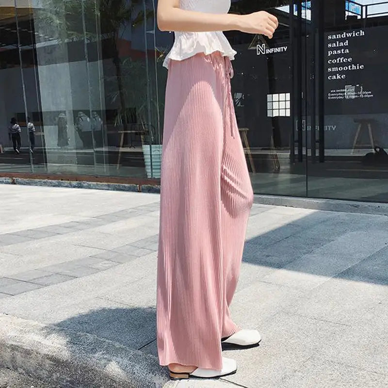rosa plissierte, weit geschnittene Sommerhose für Damen mit einem weich fallenden Stoff, elastischem Bund und Detail der seitlichen Schlitzöffnung