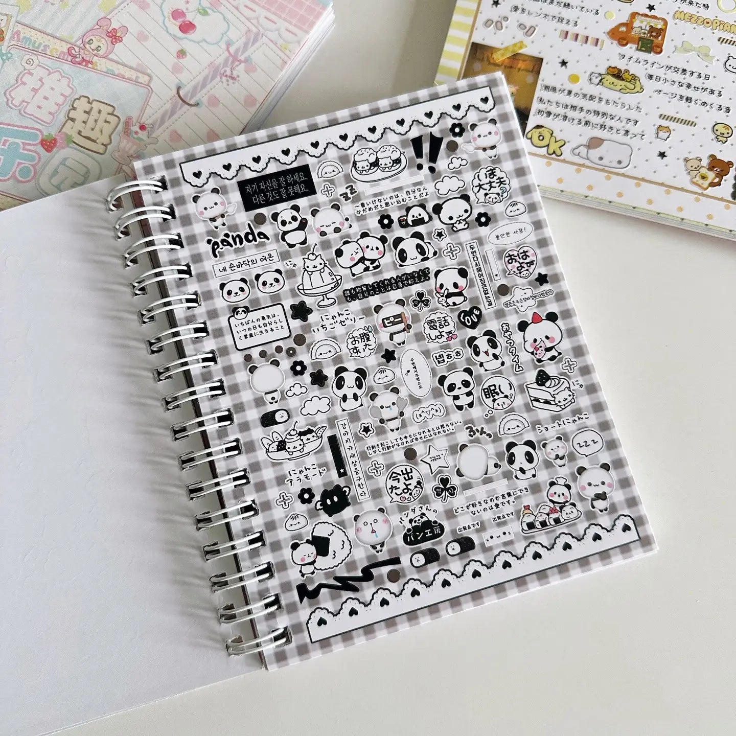 Ein schwarzer-weißer Panda-Themen-Stickerbogen aus „kawaii kpop sticker book spiral journal stationery“, der verschiedene niedliche Designs mit Pandas und Lebensmittelteilen auf einem karierten Hintergrund zeigt.