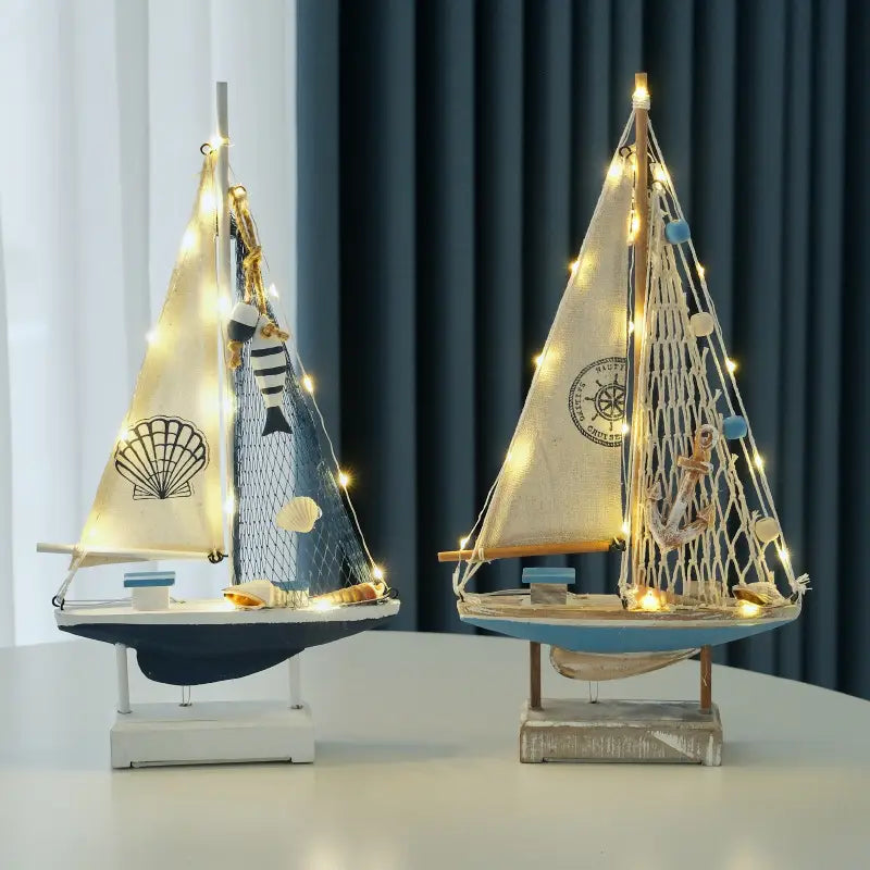 Zwei Modelle einer Deko im mediterranen Stil aus Holz mit LED-Licht für Segelboote, verziert mit Lichterketten, Muscheln, Netzen und Ankern.