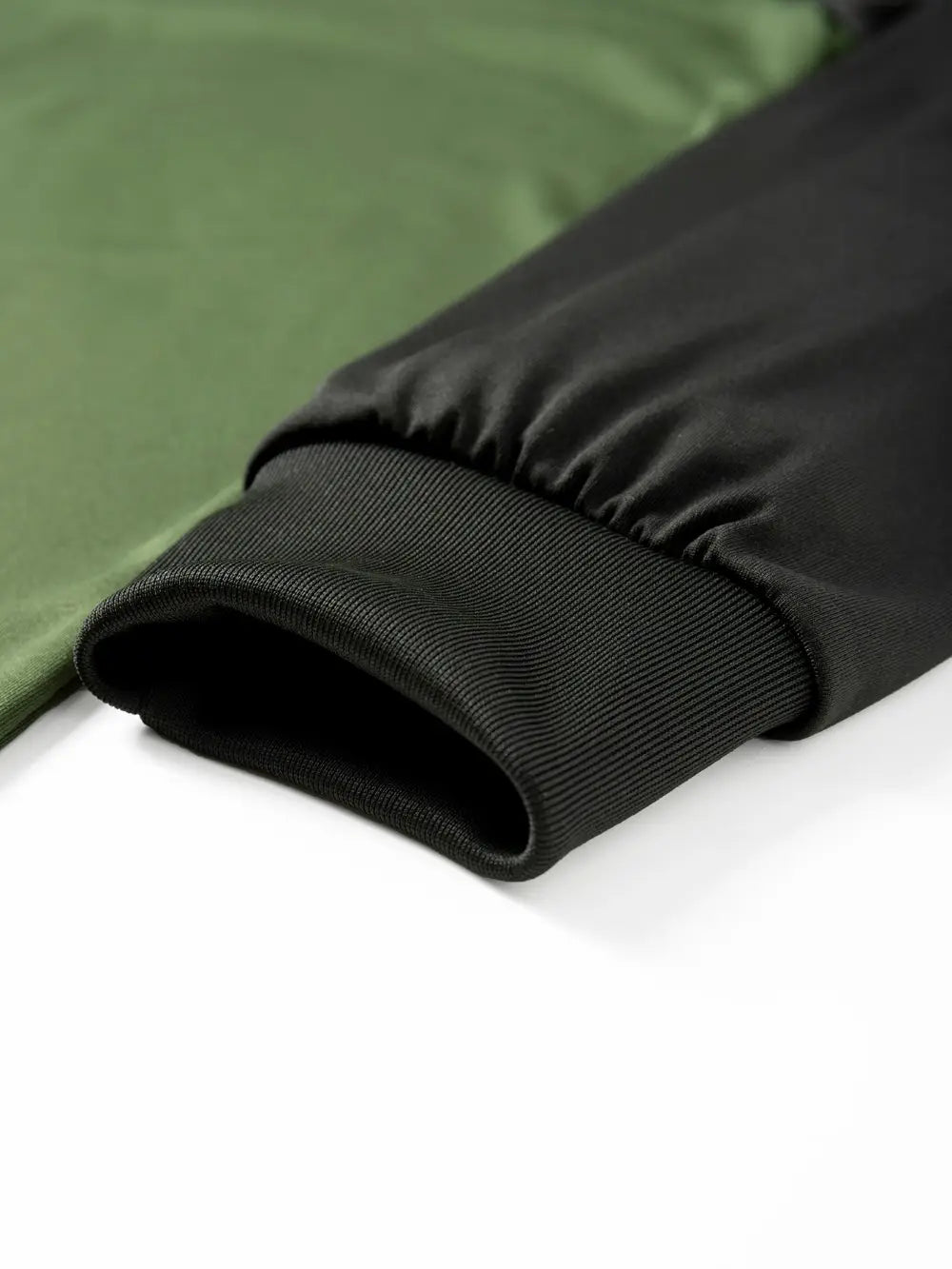 Herren-Raglanshirt mit langem Ärmel, mit einem schwarzen gerippten Strickbündchen an einer grünen und schwarzen Bomberjacke.