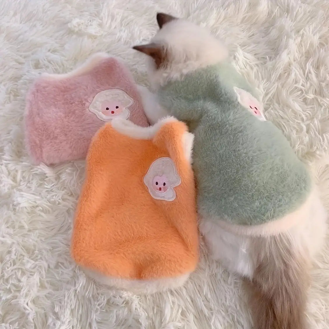 Chalecos de gato suaves y mullidos en rosa pastel, naranja y verde menta con apliques de nubes blancas, diseñados como suéteres de invierno esponjosos y mullidos para ropa de gatitos y accesorios para gatos