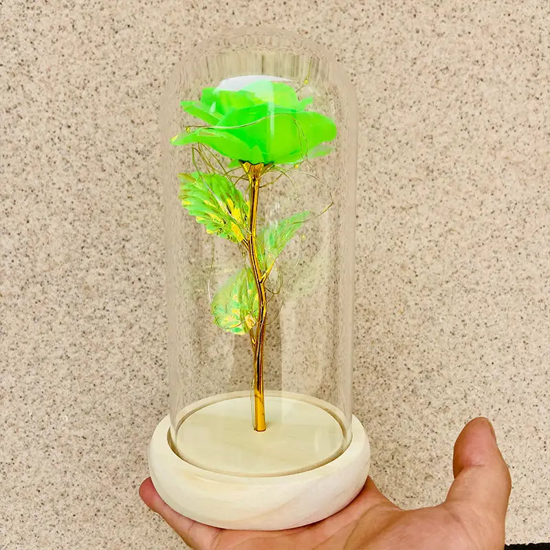 Eine leuchtend neongrüne LED-Rose mit goldenem Stiel und Blättern, umschlossen in einer klaren Glaskuppel, auf einem weißen Marmorsockel, im „Eternal Gold Rose Glass Dome Led Light Gift“