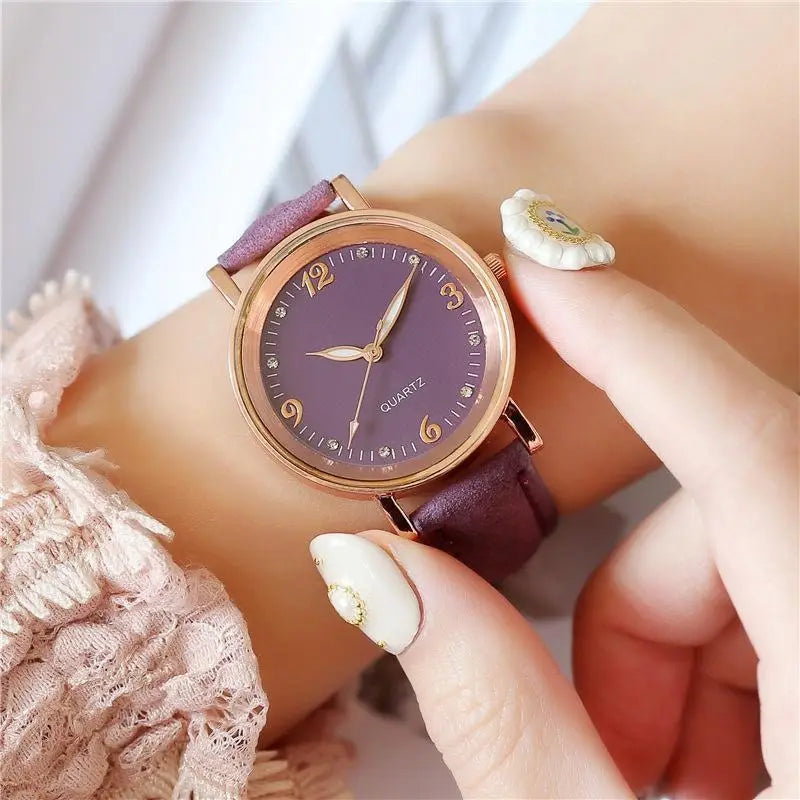 A women quartz watch with a rose gold dial, purple dial, matching leather band, elegant gold numerals, and small diamond accents.