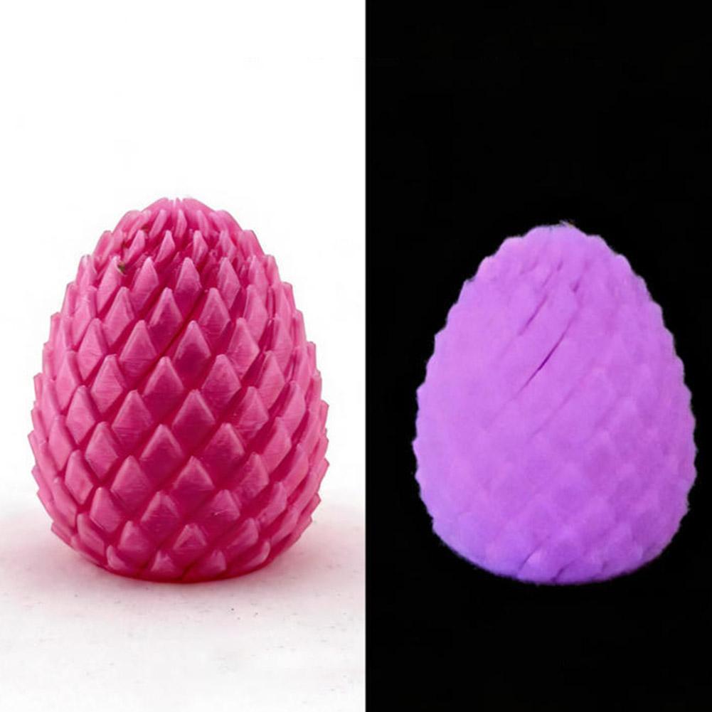 A pink textured articulated dragon egg fidget toy with a diamond-patterned surface glowing purple in the dark viewed from the front.