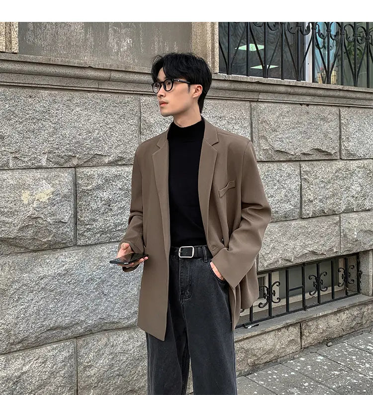 Una blazer oversize de poliéster color canela para hombres, con ajuste relajado, hombros estructurados y diseño de doble botonadura, adecuada para uso casual.