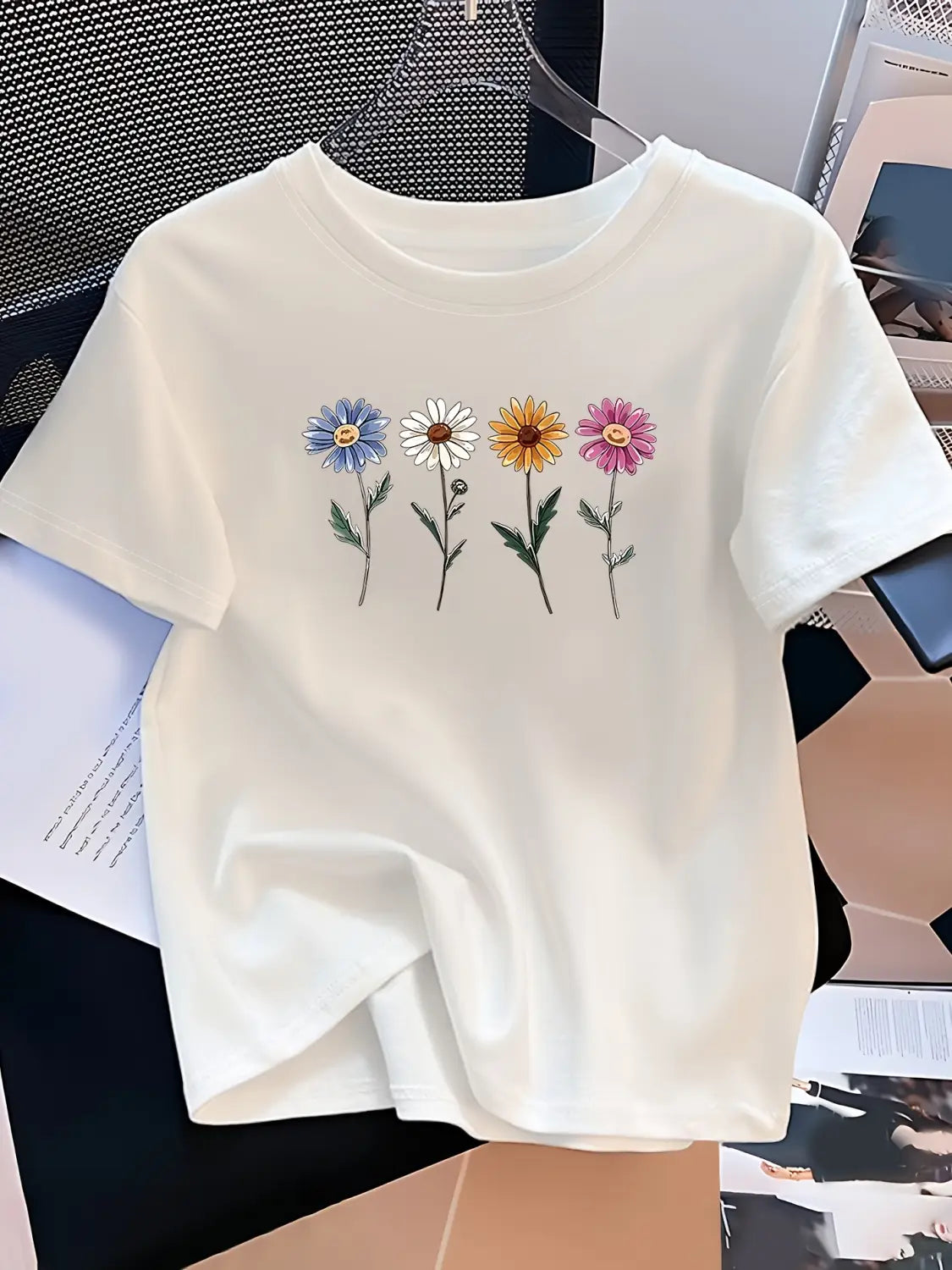 A white short-sleeved t-shirt for women featuring a colorful embroidered design of four daisies in blue, white, yellow, and pink with green stems.