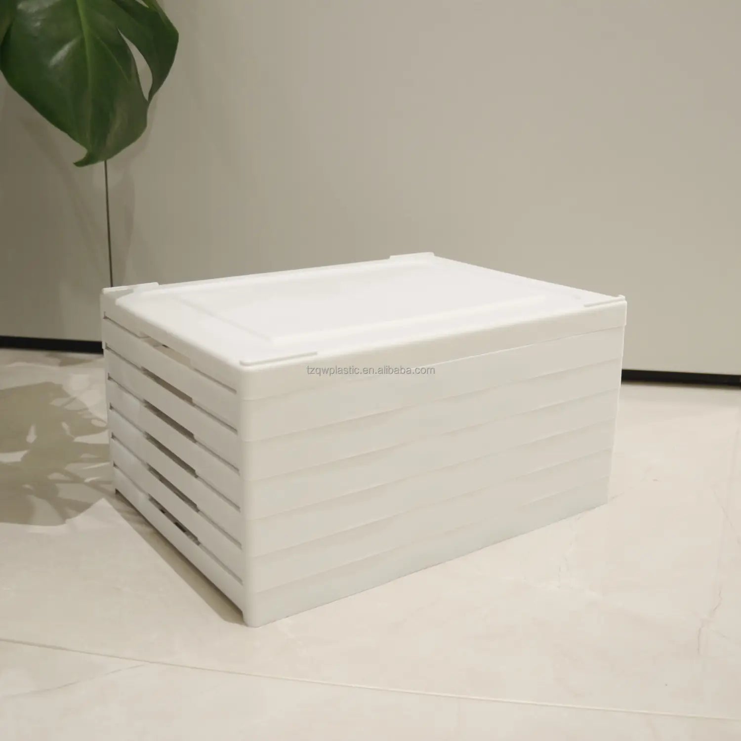 White plastic storage box with a hinged lid and horizontal ridges designed as a clear stackable shoe organizer storage box for efficient working time management.
