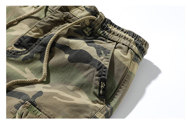Tarnfarbene Cargo-Jogginghosen für Herren aus Baumwolle in lockerer Passform, mit Kordelzug an der Taille und sichtbaren Ziernähten.