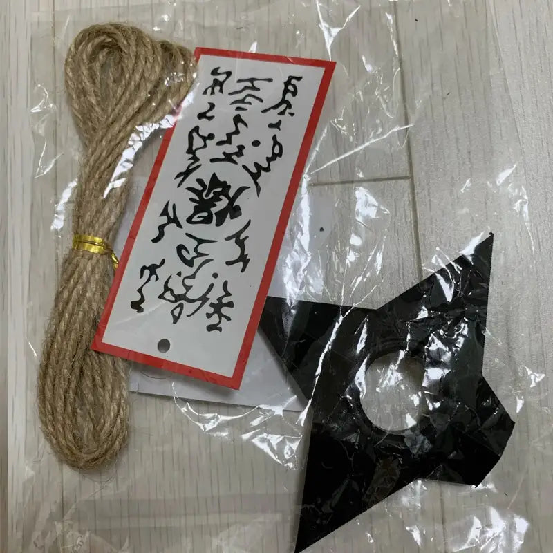 Shuriken-Ninja-Kunai-Kühlschrankmagnet aus schwarzem Kunststoff aus PVC mit zugespitzten Kanten und einem zentralen Loch.