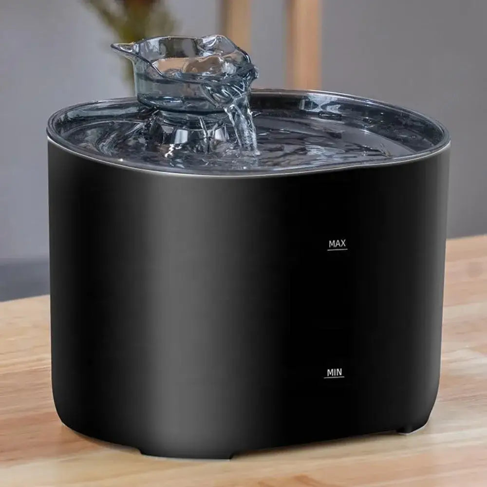 Fontaine d’eau pour chat cylindrique noire avec pompe silencieuse et bec en verre transparent, laissant s’écouler l’eau dans le bassin d’une capacité de 2,2 litres.