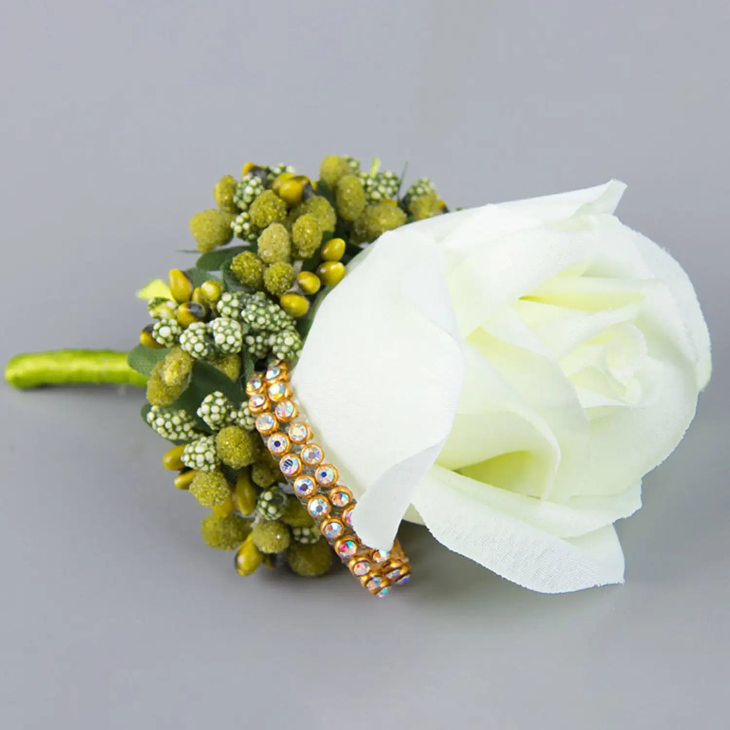 Elegant white artificial silk rose boutonniere adorned with greenery and a sparkling gold rhinestone band for a blue wedding corsage.