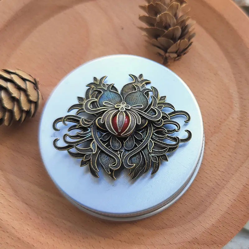 Antique bronze-colored filigree brooch with intricate floral design and a central red and gold embellishment from the turquoise floral palace jewelry collection.