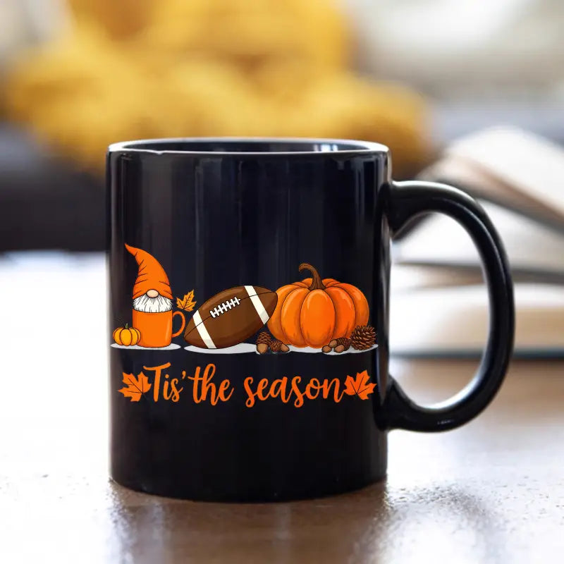 Black ceramic Easter egg coffee mug featuring a festive autumn design with an orange gnome, football, pumpkin, and the phrase tis the season in orange script.