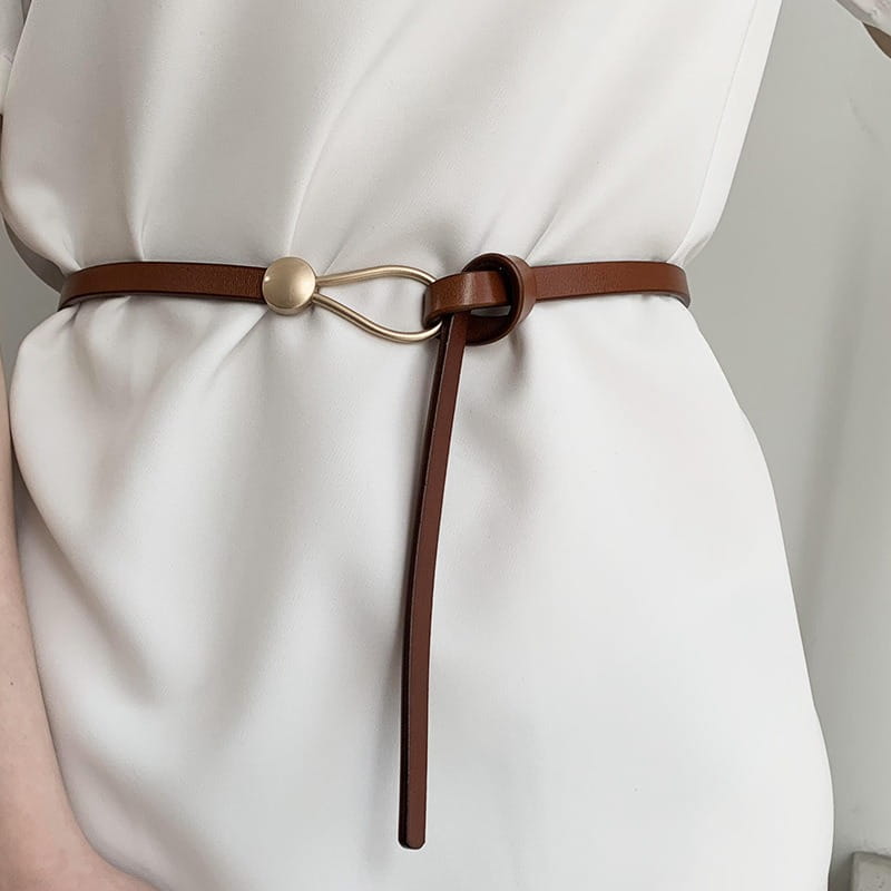 Ceinture en cuir PU fine marron pour femmes, au style minimaliste, avec une boucle en métal doré présentant une fermeture à forme ovale et un petit bouton circulaire en accent.