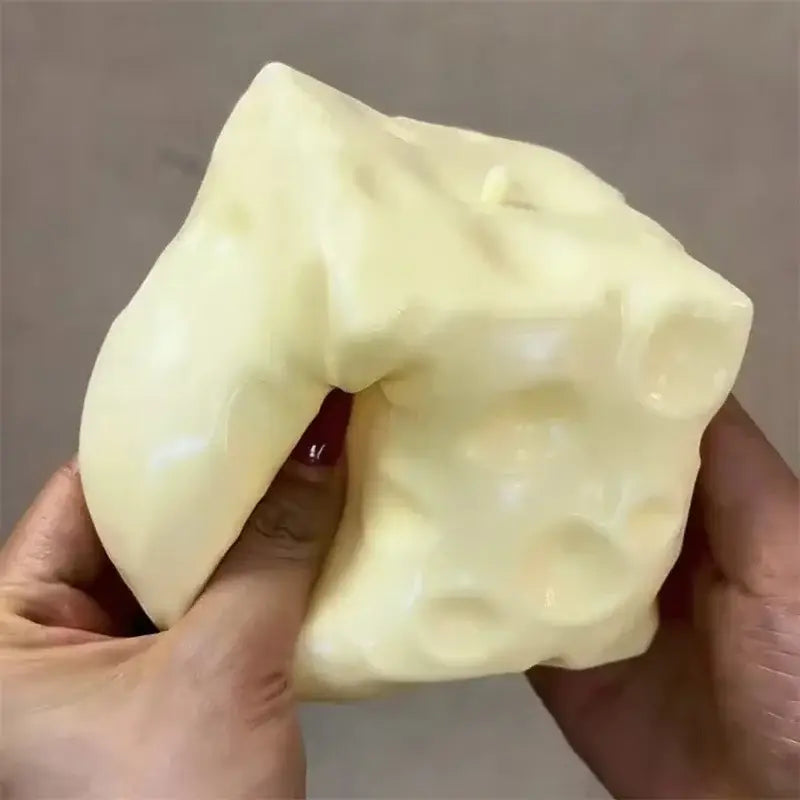 Un juguete antiestrés esponjoso con forma de queso, de color amarillo pálido, con una superficie de plástico brillante y orificios característicos.