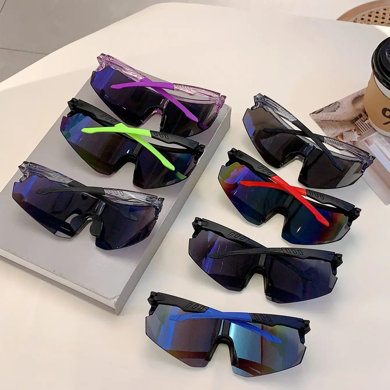 Ensemble de lunettes de soleil de sport surdimensionnées pour cyclisme, avec des montures aérodynamiques noires élégantes et translucides, des branches en violet vibrant, vert néon, rouge et bleu, ainsi que des verres à dégradé réfléchissant, conçues pour le cyclisme.