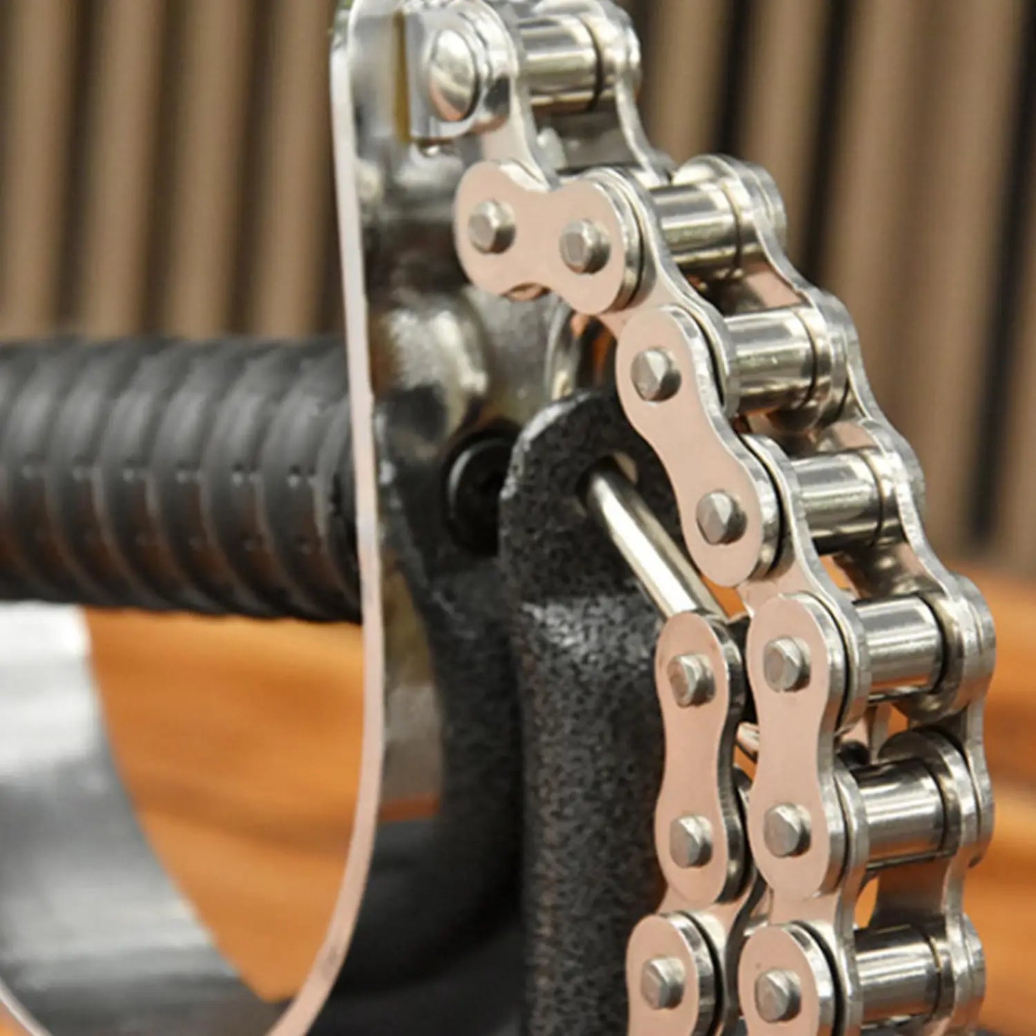 Shiny silver metal arm wrestling training equipment forearm grip exerciser featuring a bicycle chain with polished links and riveted plates.