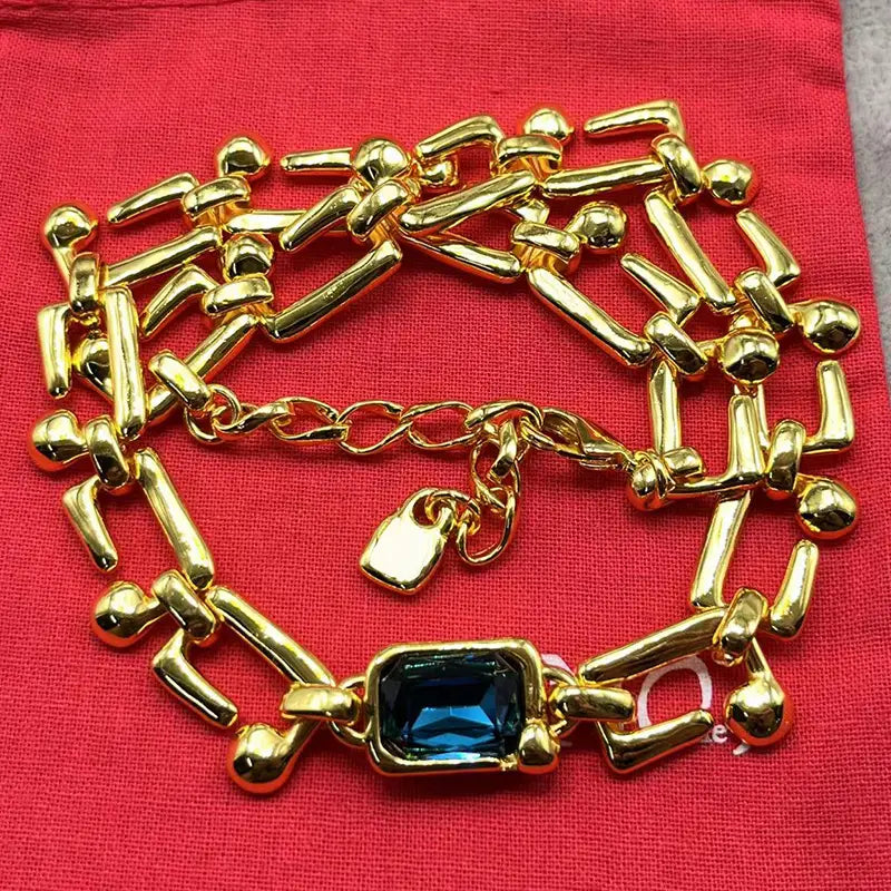 Gold-toned chain bracelet from the crystal pendant jewelry set featuring bold geometric links, a central rectangular blue gemstone, and a small padlock charm.