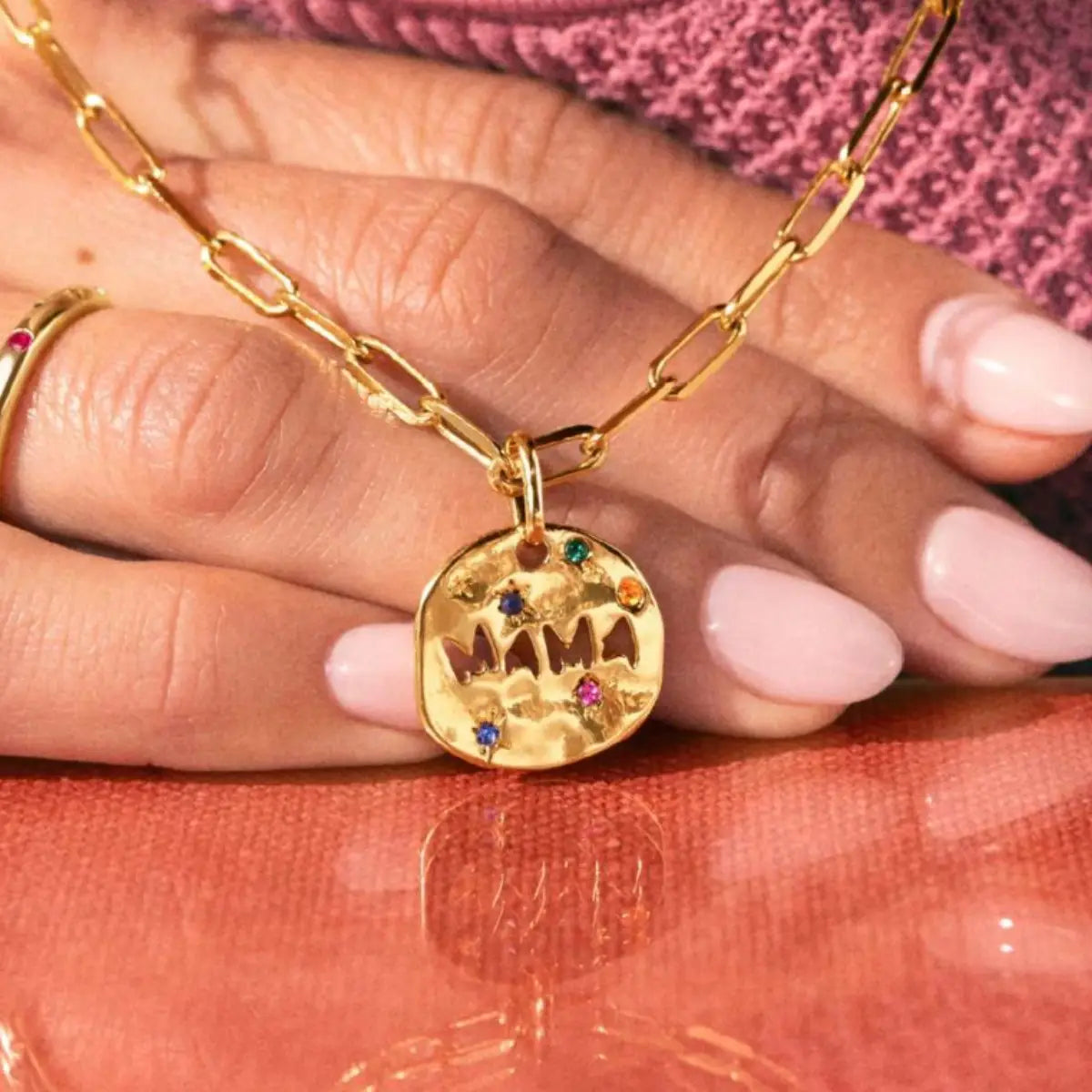 Collier en acier inoxydable doré avec chaîne à maillons, doté d'un pendentif rond à texture, gravé « Mama » et orné de pierres précieuses colorées, au sein de la collection de colliers à pendentif en pierre précieuse « Mama » en acier inoxydable.