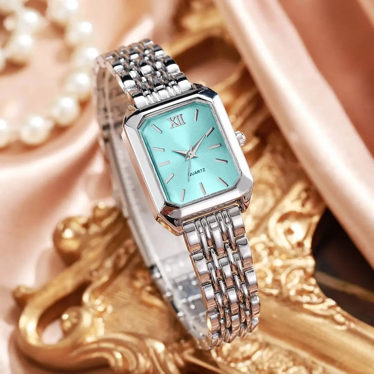 Women gold rectangle quartz watch with a sleek silver-toned rectangular case, turquoise face with roman numeral hour markers, and an elegant mesh-link bracelet.