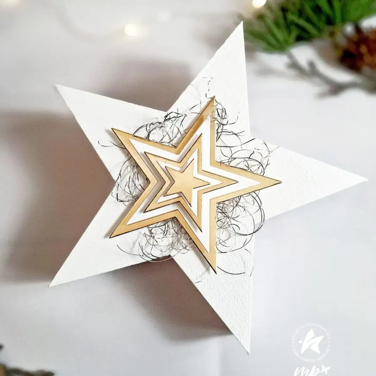 White paper star ornament with layered gold metallic star design and black wire curls featured in winter animal metal cutting dies for scrapbooking.