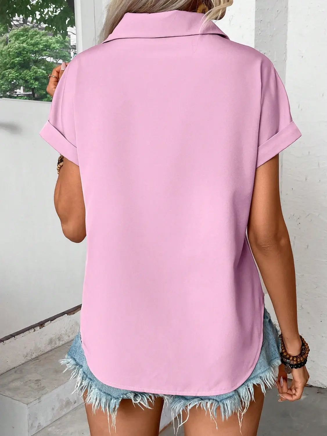 a soft pink short sleeve button up blouse for women featuring a relaxed fit and rolled cuffs highlighting its sleeve length design