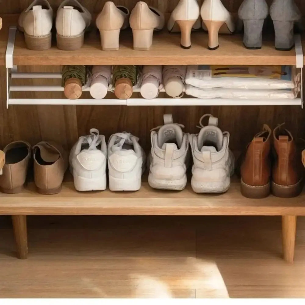 White metal telescopic shoe rack with three shelves holding various pairs of shoes for metal storage organizer use.
