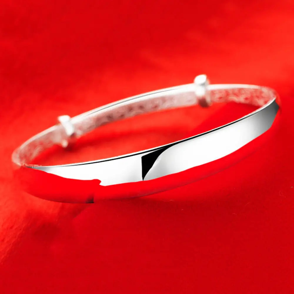 Sterling silver round bangle bracelet for women with a sleek silver tone polished finish and distinctive angular cutout design.