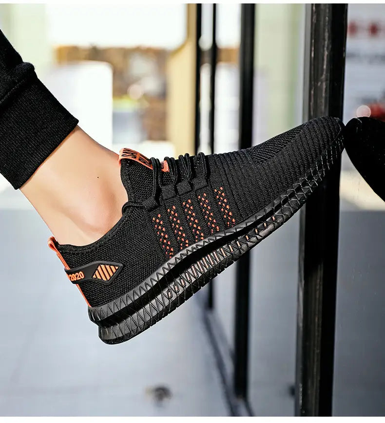 Herren-Atmungsaktiver legere Strick-Sneaker in Schwarz mit orangefarbenen Akzenten und einer strukturierten Gummisohle.