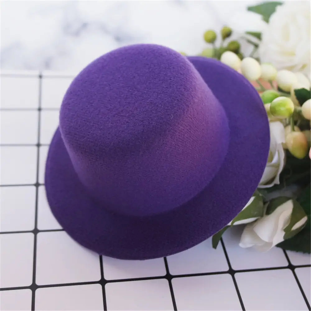 Un chapeau haut-de-forme en feutre violet, à calotte arrondie et bord large, conçu comme accessoire de mode pour des poupées de 60 cm.