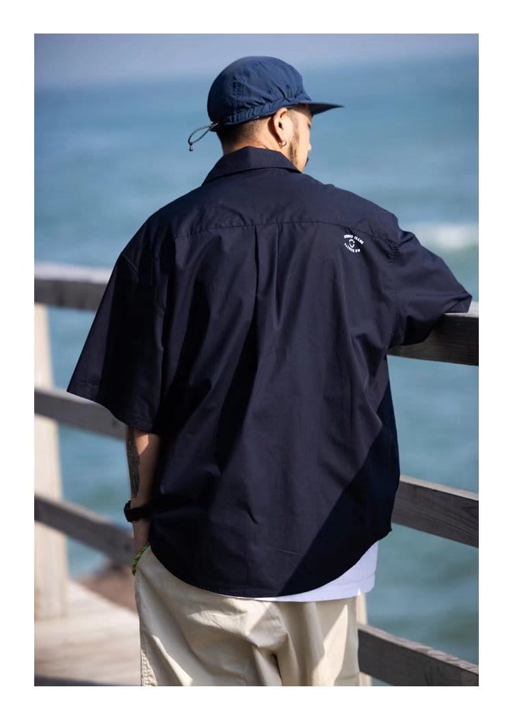 Navy blue mens casual short sleeve button up shirt shown from the back with a subtle embroidered logo on the collar.