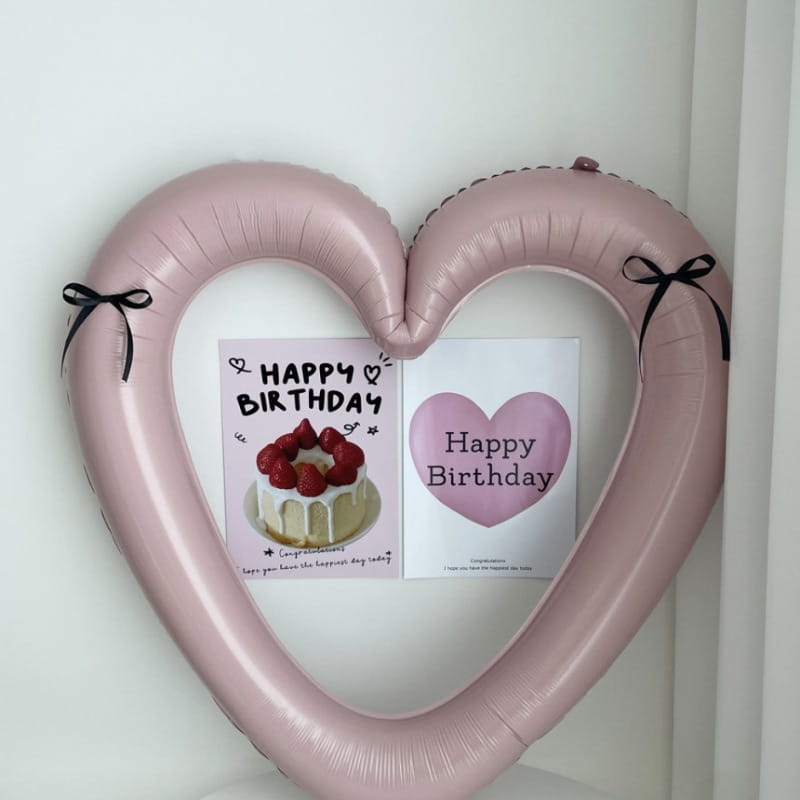 Un globo de lámina para marco de foto de corazón rosa suave de 40 pulgadas con lazos de cinta negra en cada extremo, fabricados con material inflable