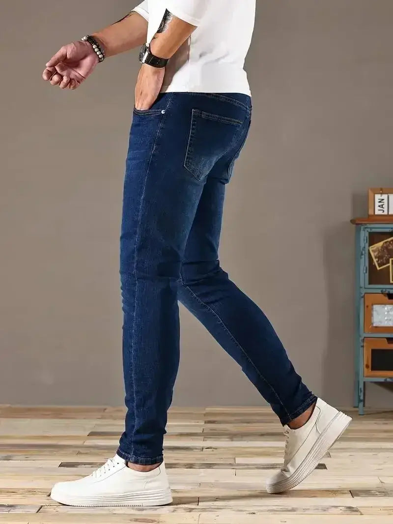 Jeans en denim bleu foncé coupe slim pour homme réalisés en denim avec une atténuation subtile au niveau des cuisses.