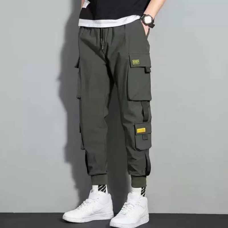 Pantalons cargo vert olive foncé pour hommes avec plusieurs poches et des empiècements à accent jaune, conçus comme des sweatpants décontractés à taille à cordon de serrage.