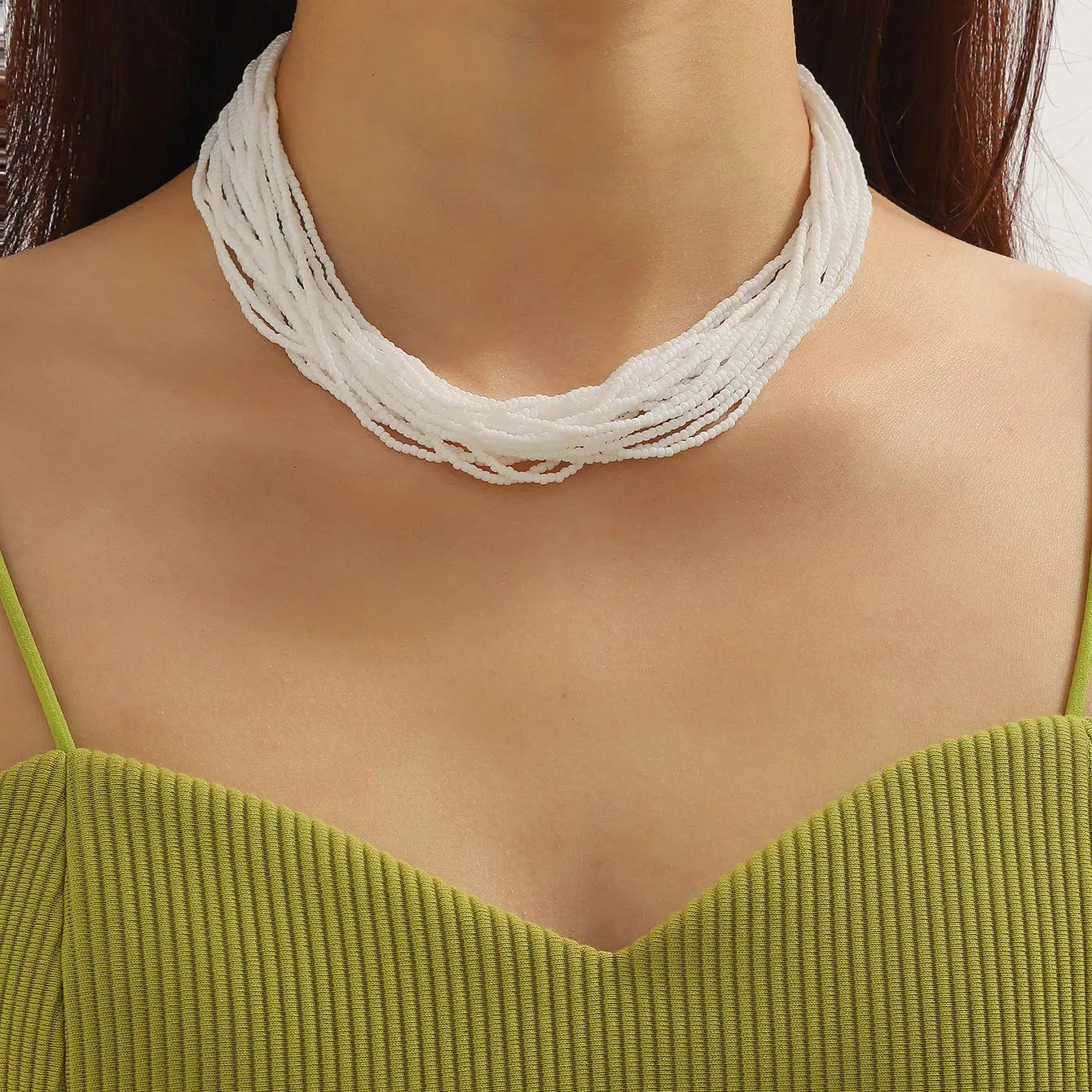 Collier ras du cou boho à plusieurs rangs avec perles blanches, comportant plusieurs brins tressés pour un accessoire élégant.