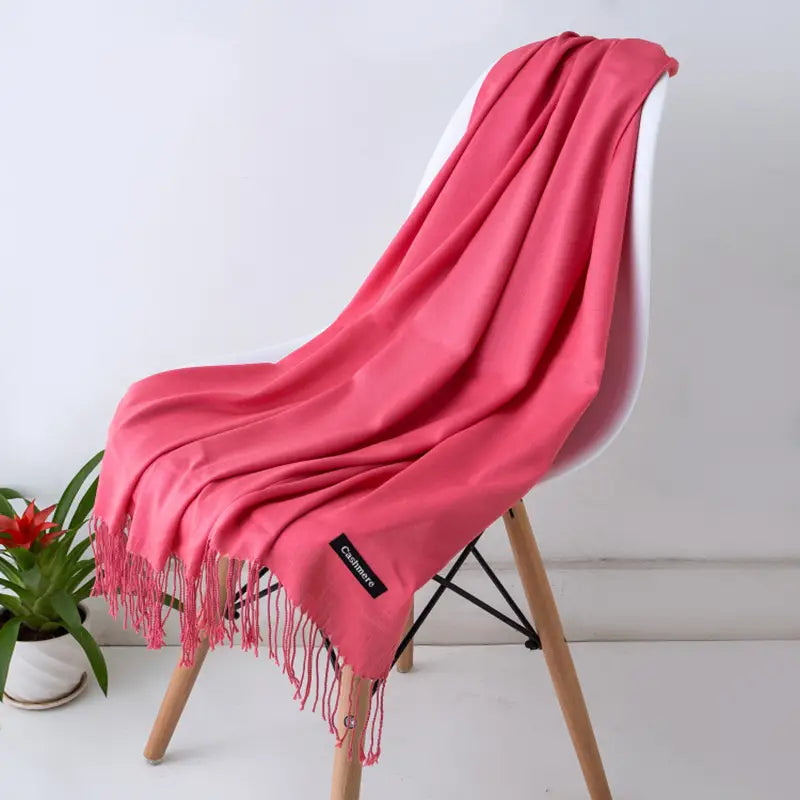 くすみのあるサンゴ色ピンクの女性用カシミヤ風冬用スカーフ／ショールです。カシミヤ素材で作られており、繊細なフリンジと控えめなブランドタグが付いています。