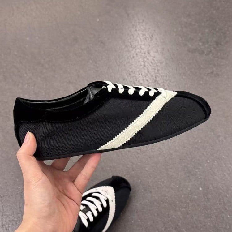 Baskets décontractées en cuir pour femmes noires et blanches, avec un bout de pied noir brillant, une tige en tissu texturé et une bande zigzag couleur ivoire sur toute la longueur du côté.