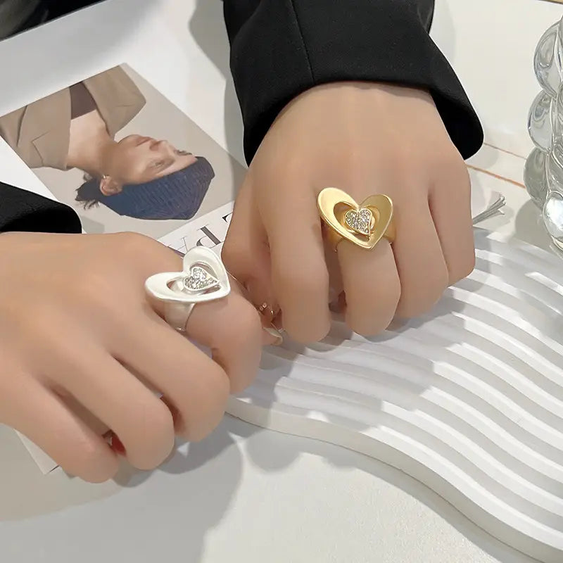 Anillo ajustable con forma de corazón en oro y blanco, con detalles brillantes de pedrería incrustada en metal dorado