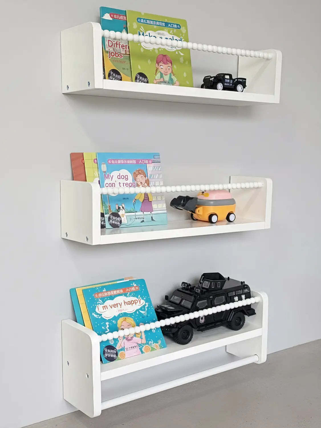 白い木製の浮遊式ブックシェルフ3点セット。ビーズで縁取られたエッジで壁掛け式、子どもの本や玩具の車両を収納できます。