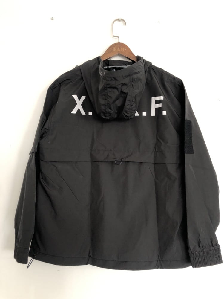 Veste imperméable à capuche tactique techwear noire x.a.f, montrant la face arrière réalisée dans une matière durable conçue pour assurer une protection en extérieur.