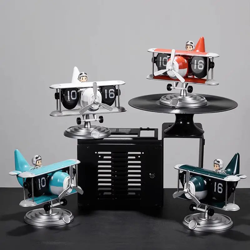Set of four vintage-style airplane flip desk clocks featuring miniature pilot figures and bold black-and-white numerals on their biplane wings for table decor.