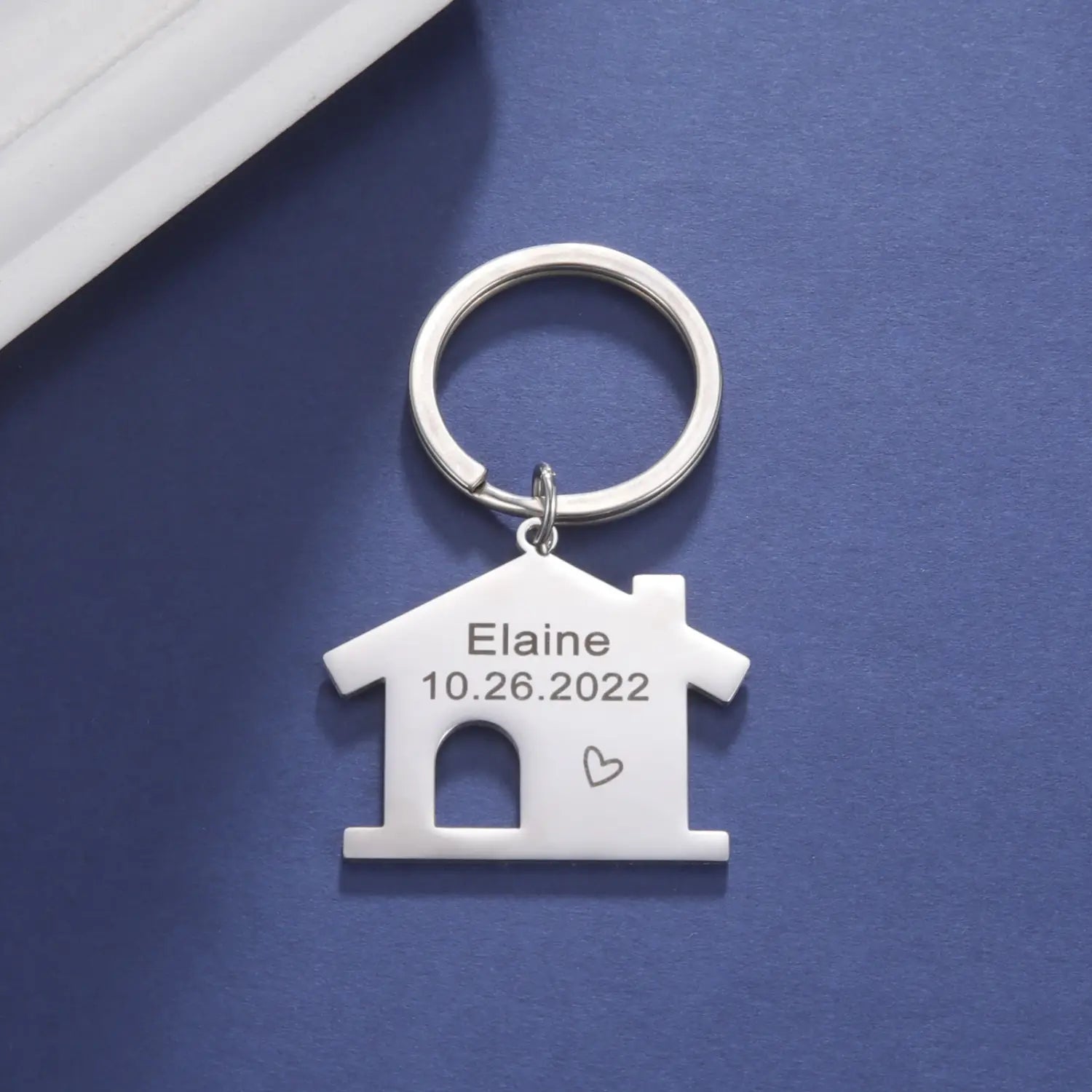 Silver house-shaped keychain made of metal with engraved name and date personalized as a custom couple gift.