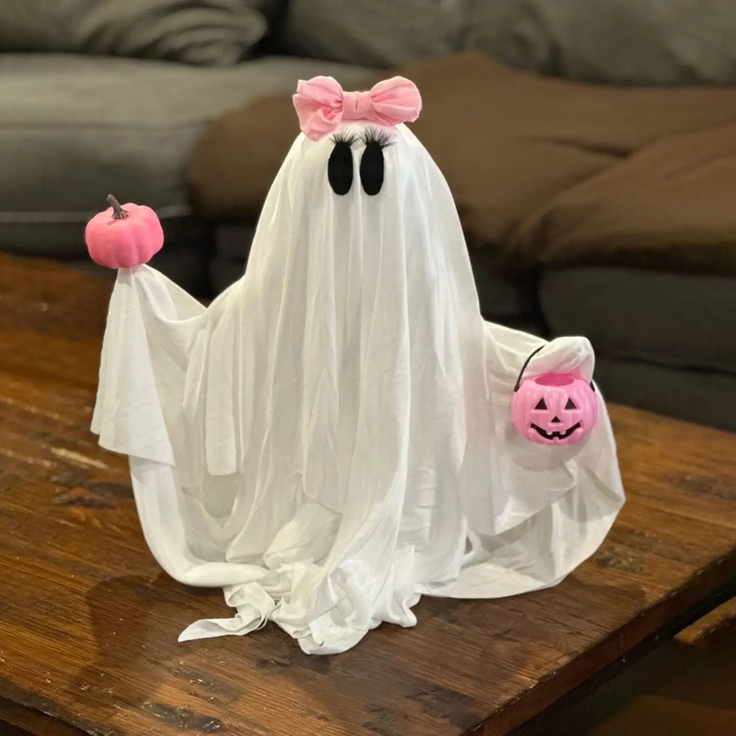 eine weiße Stoff-Geisterfigur mit einer rosa Schleife, die einen kleinen rosa Kürbis und einen rosa Kürbis-Jack-O-Lantern-Korb hält, als rosa Kürbis-Geister-Halloween-Tischdekoration