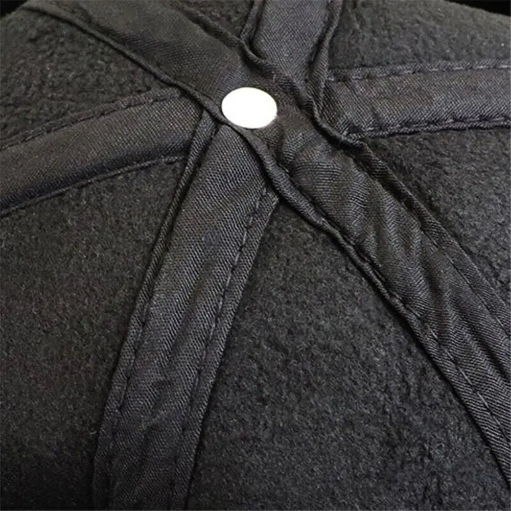 中央に白いボタンを配した、冬の防寒用の調節可能な黒のウールキャップ（メンズ用レザーベースボールキャップ）。