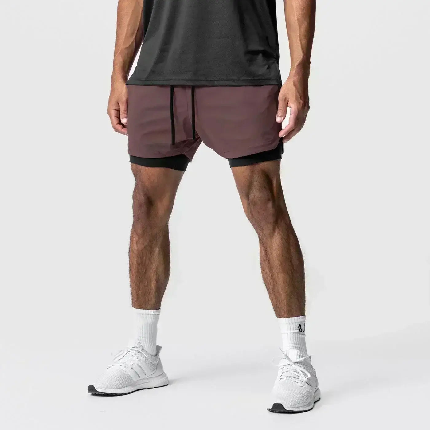 Hombres, pantalones cortos atléticos de dos capas burdeos y negros 2 en 1 para gimnasio con cintura elástica y trabilla para la toalla, diseñados para uso en entrenamientos.