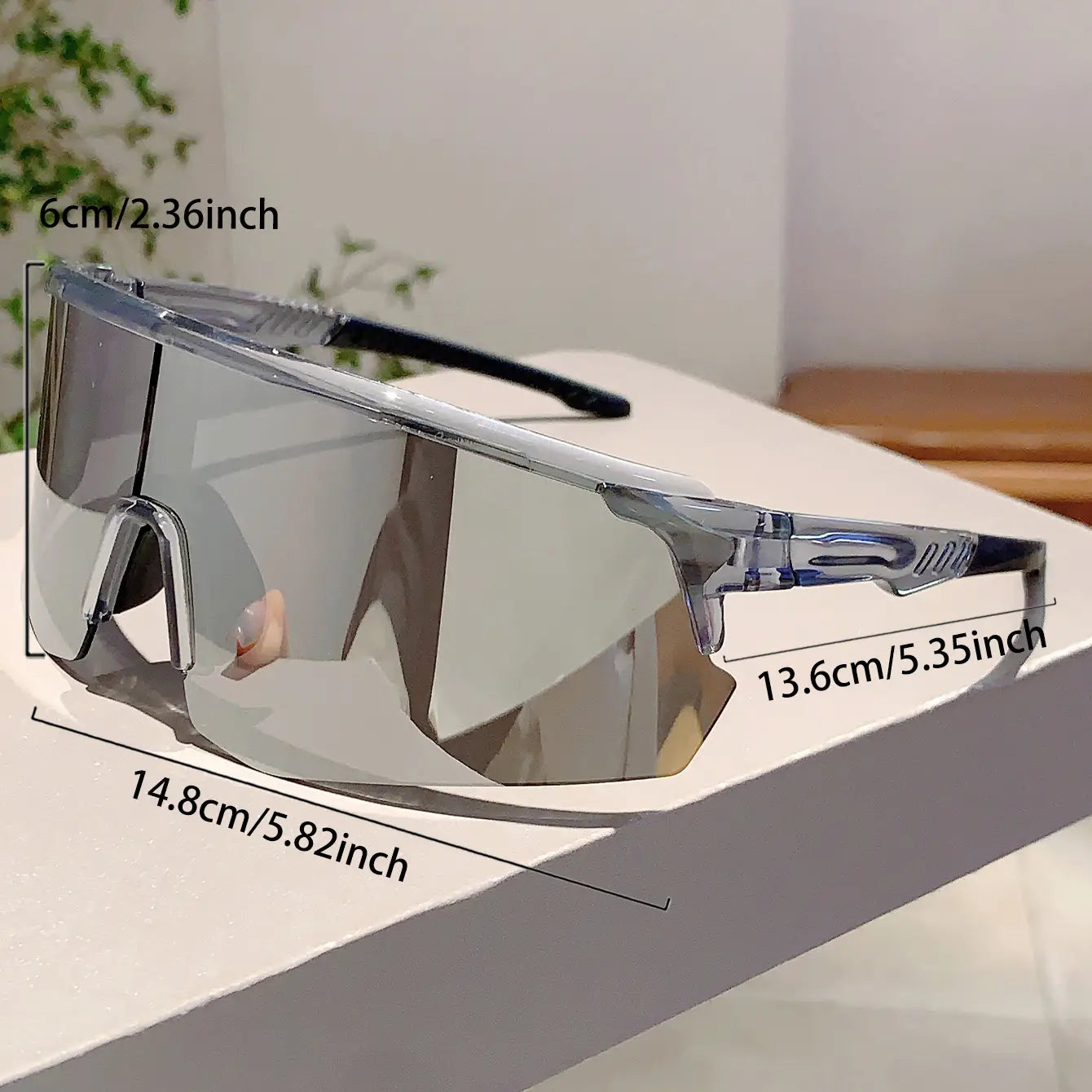 Lunettes de soleil de sport surdimensionnées à monture transparente, verres argent réfléchissants et extrémités des branches noires, conçues comme des lunettes de cyclisme à effet miroir.