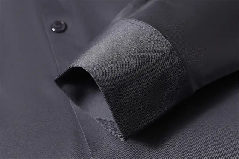 Camisa de vestir para hombre sin arrugas gris oscuro, con parte delantera abotonada y puño de tela a juego, doblado con esmero.